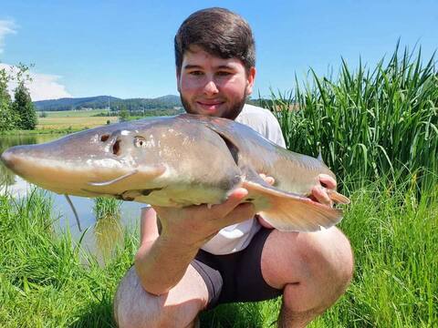 Jungfischer mit Stör am Ufer