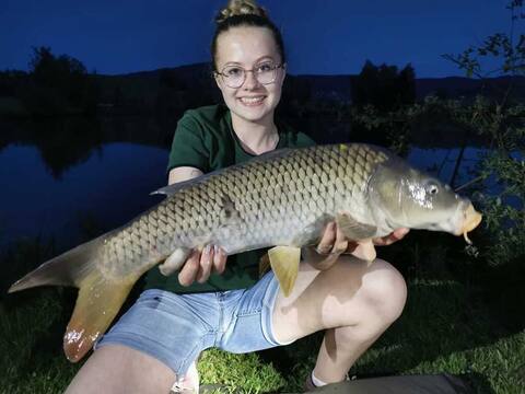 Jungfischerin hält am Abend einen großen Karpfen